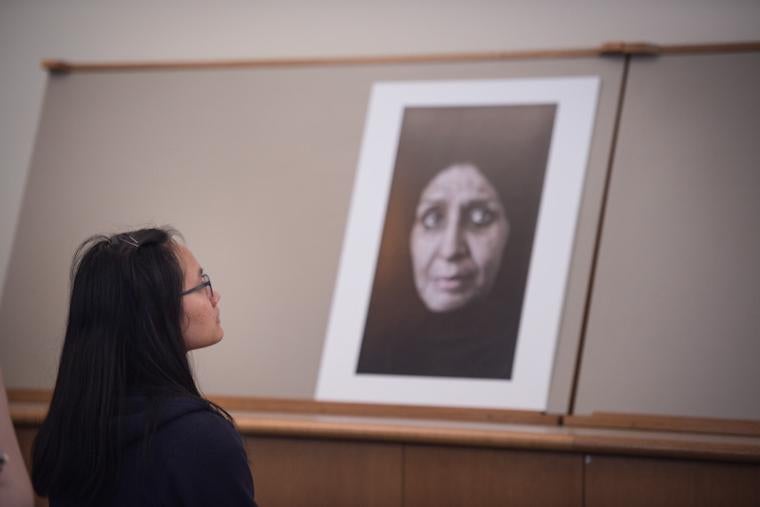 A student studies a large photo of the face of an older woman