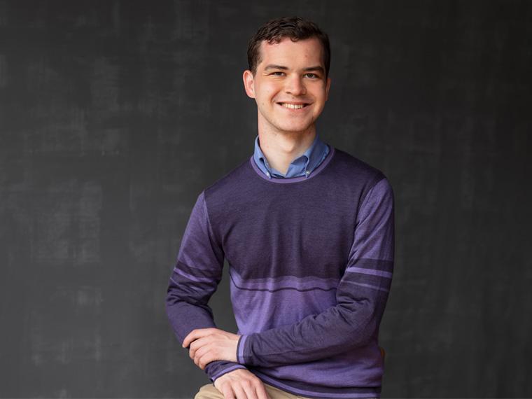 a person wearing a purple shirt smiles at the camera