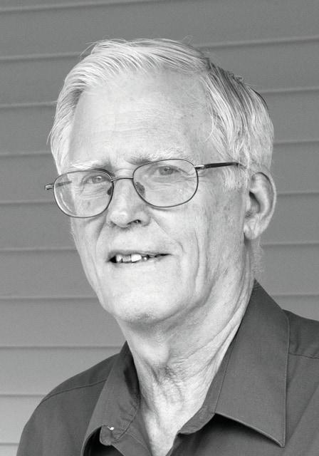 Alan Carroll poses in black and white photo wearing dark shirt.