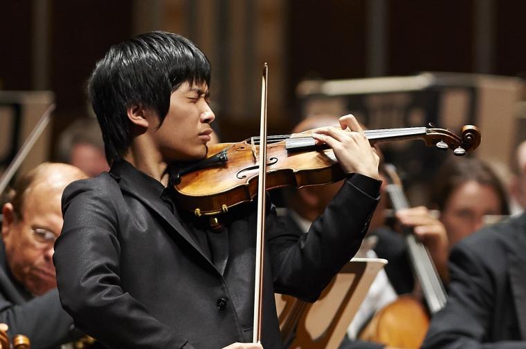 Young violinist performs with orchestra