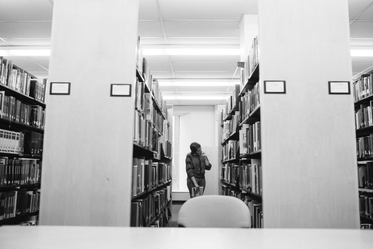 Student looking at books in the library 