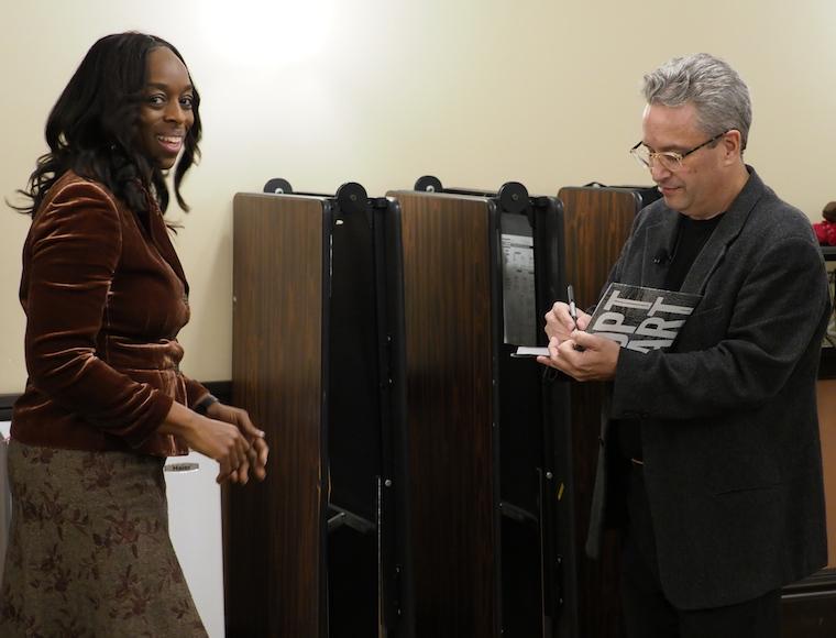 Professor signs book for college president.