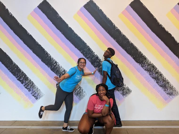 Students pose in front of museum artwork.