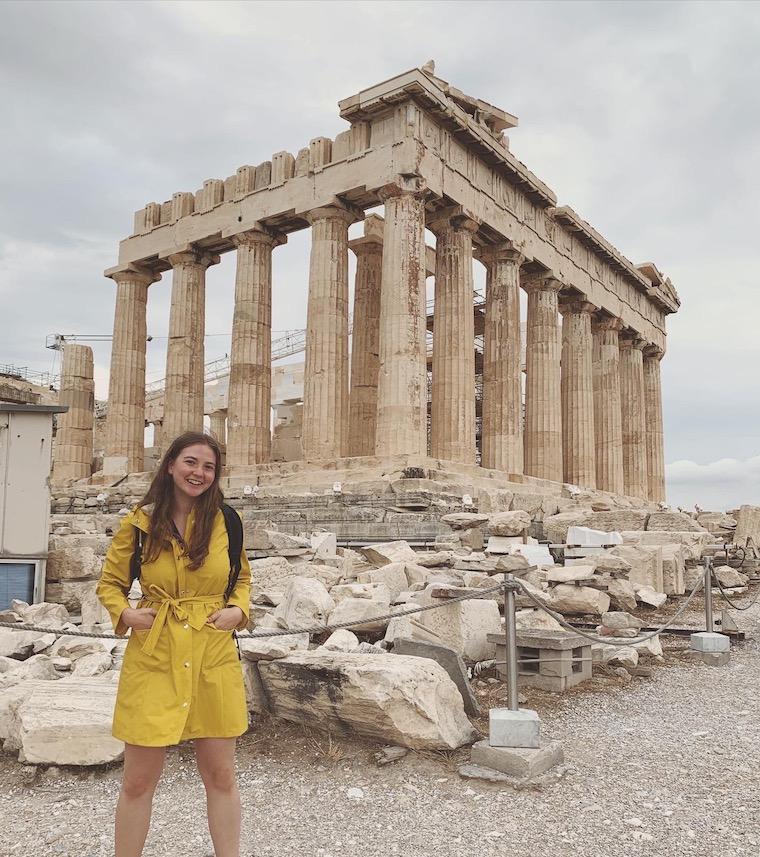 Woman standing in front of ancient stone building.