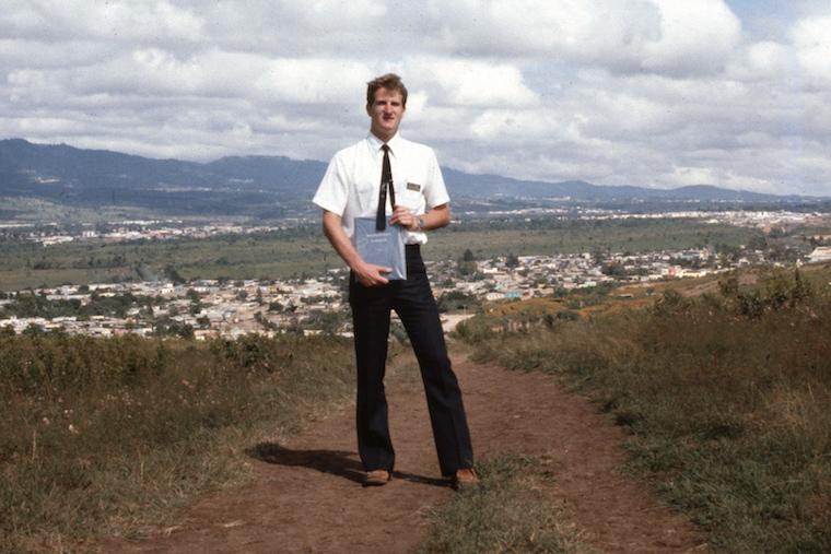 Man standing in front of landscape with mountains.