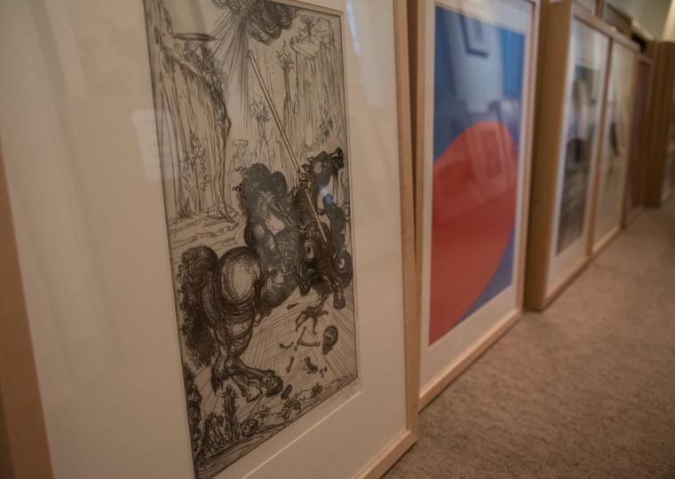 A row of prints and paintings on a floor.