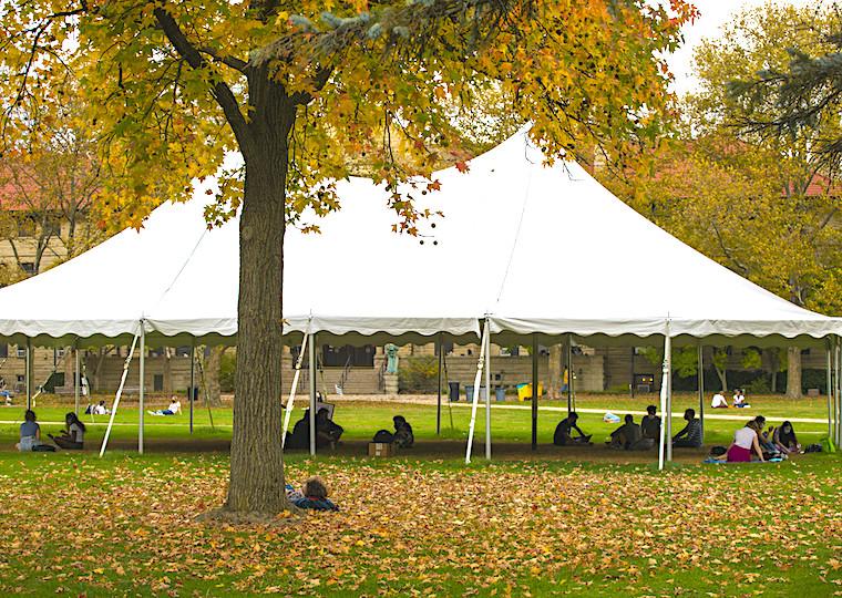 A large tent with people in it on a fall day.