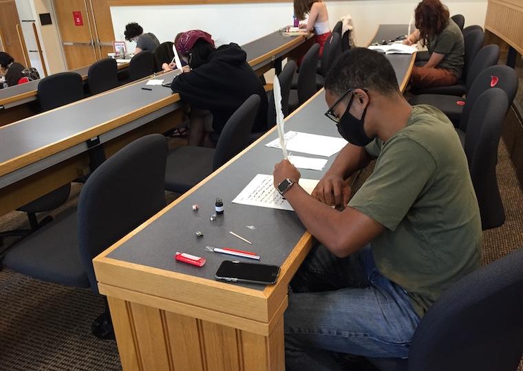 Students write with quill pens in class.