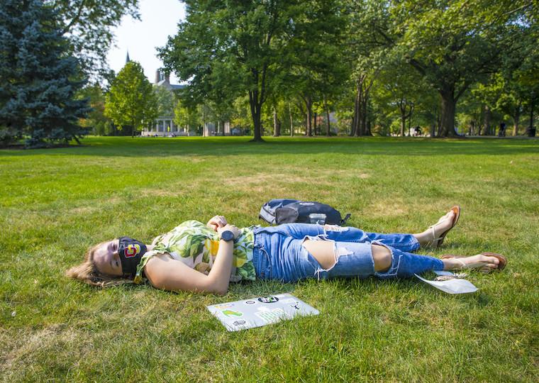 A girl laying in the grass in the park.