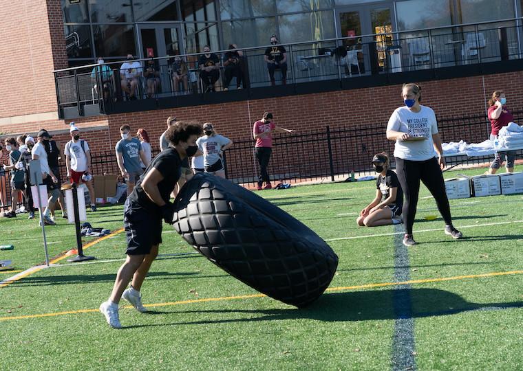 a student flips a large truck tire.
