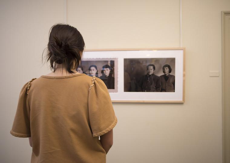 A student looks closely at a photo on a wall in a art museum classroom.