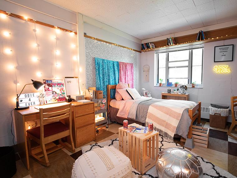 A dorm room with bed, desk, and hanging lights.