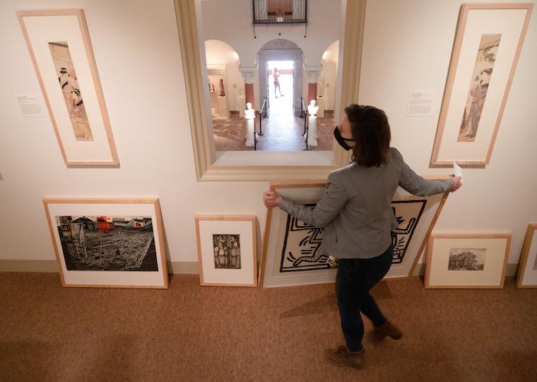 A woman holds a large painting.