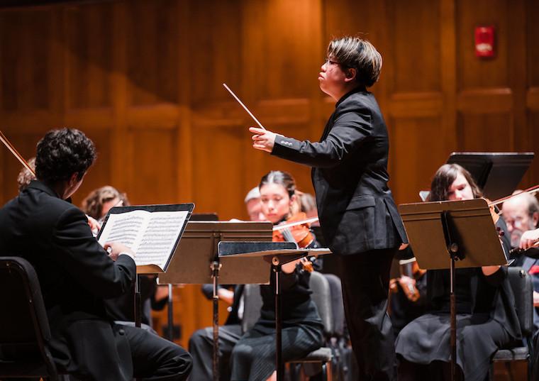 A woman conducts an orchestra.