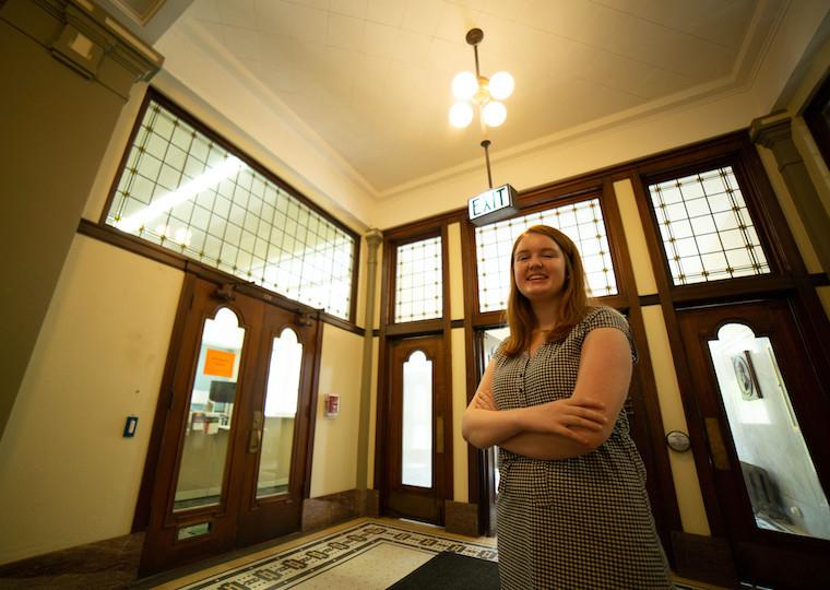 A student poses in the hallway of a large building.
