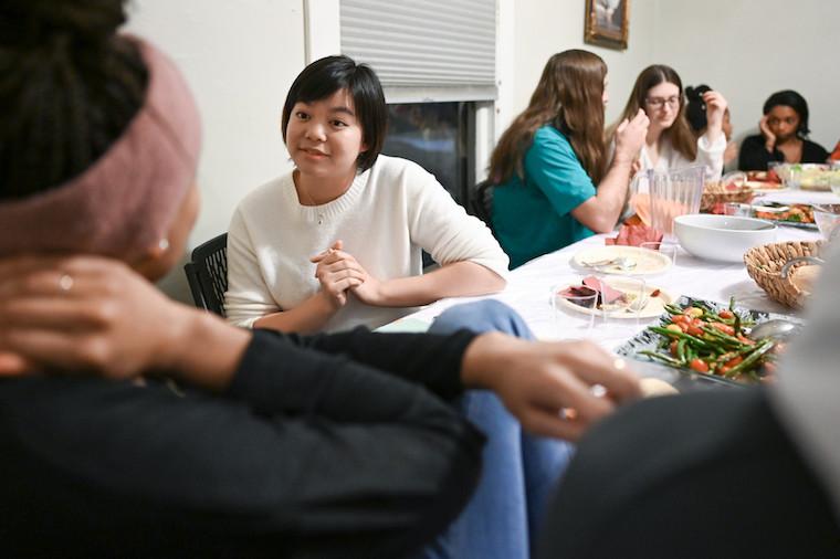 Six students sitting at a table set with food.