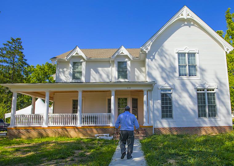 A man asks up a path to a large home.