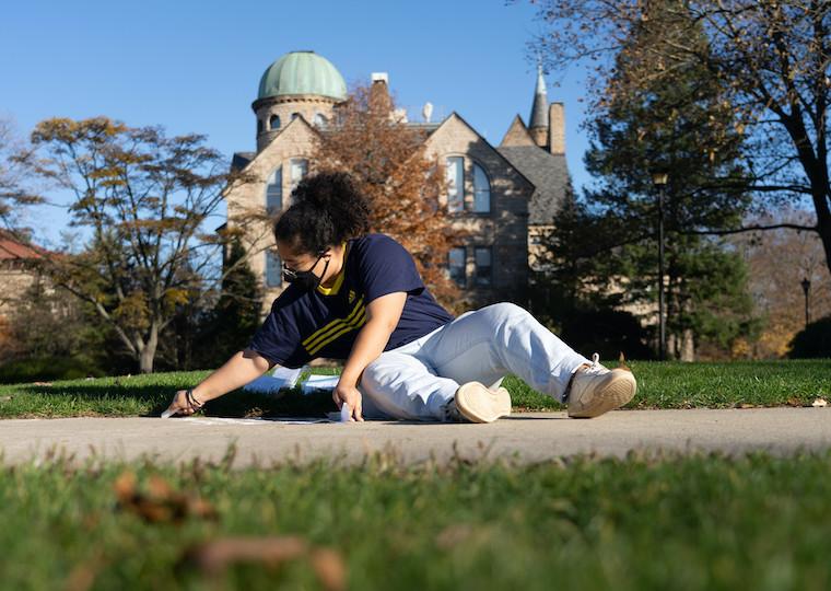 A girl draws with chalk on a sidewalk.
