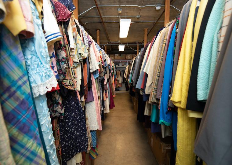 Two long rows of clothing hanging up on long pipes.