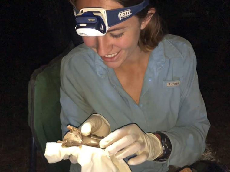woman in blue shirt holds a bat.