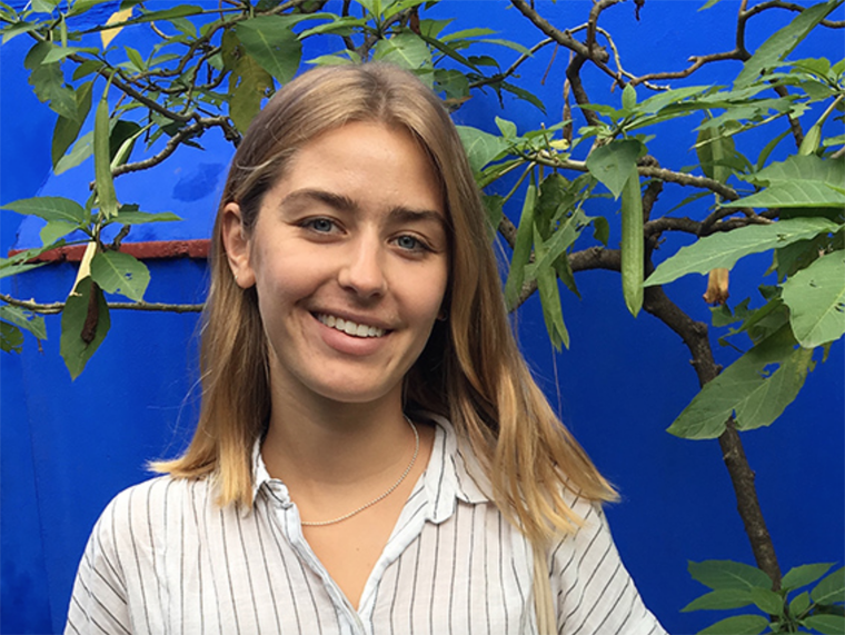 Michelle Fikrig in front of a blue background with tree branches.