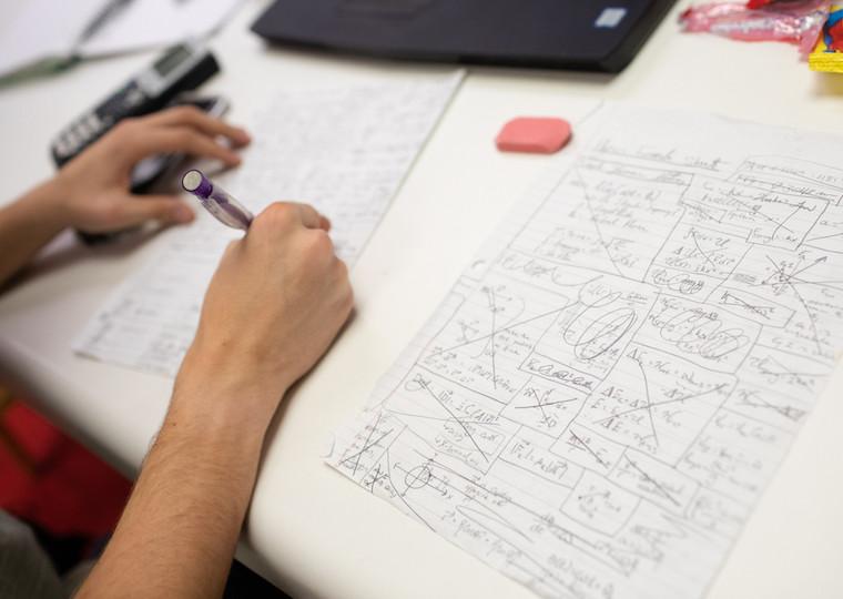 A student writes on sheets of paper.