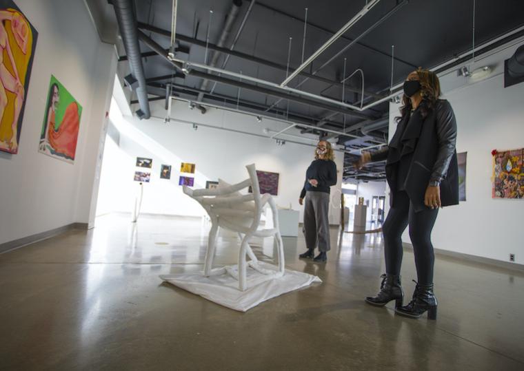 Two women stand in the middle of an art exhibit.