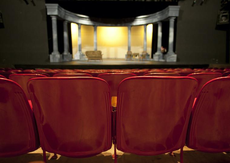 An empty auditorium facing a stage with columns on it.