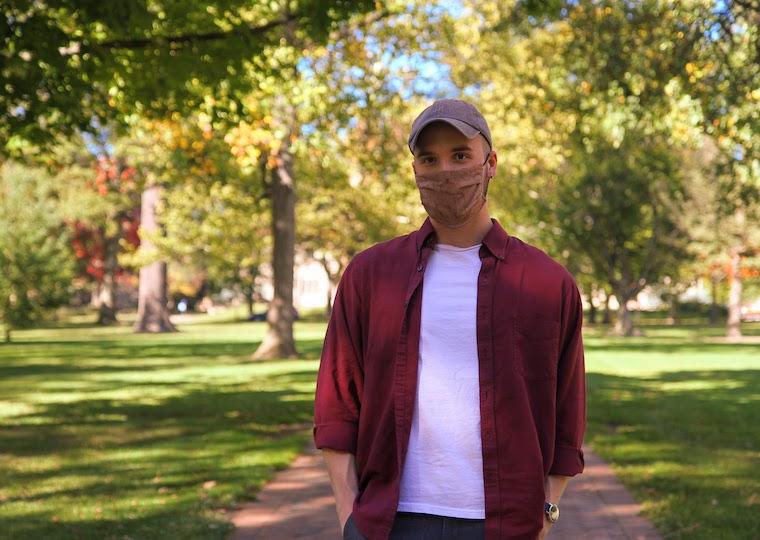 A student stands with his hands in his pockets.