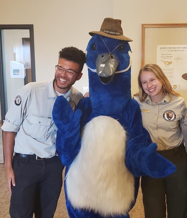 Two people post with bird mascot.