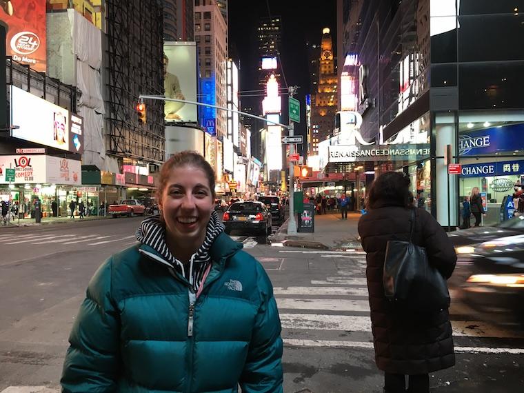 Woman standing on a city sidewalk at night in the city.