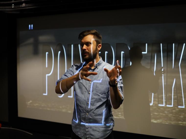 A an stands in front of a movie screen with the words of the screen on his face and body.