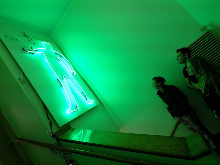 Students look at neon artwork.