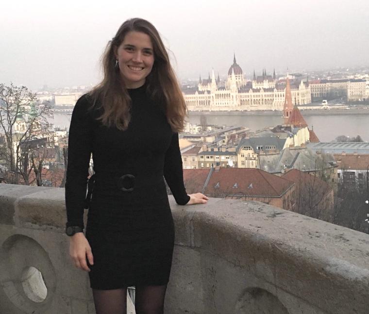Woman standing in front of stone structure.