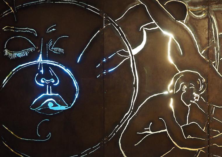 Faces, people, and shapes pressed into a metal sheet.