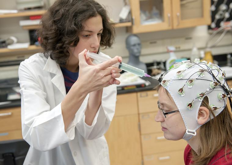 A student injects fluid into EEG electrodes