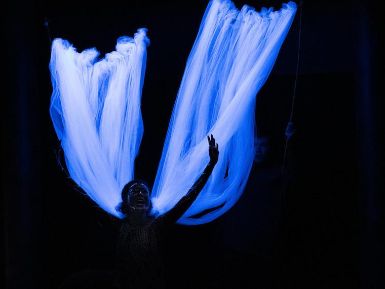 A student actor wearing shear glow in the dark wings.