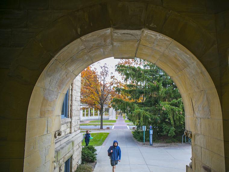 A student approaches a curved stone entrance.