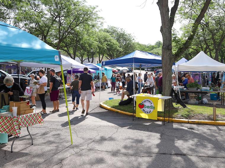 A busy street with vendors selling goods under canopy tents.