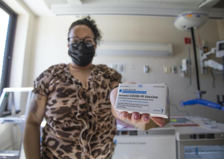 A woman holds a box containing COVID-19 vaccine.