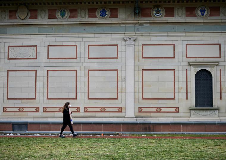A student walks in front of a large stone building.