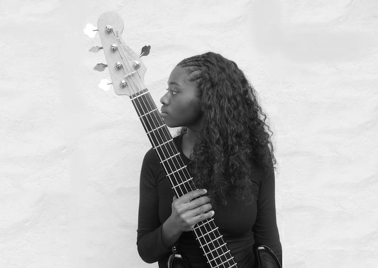A girl holds a bass guitar in a portrait.
