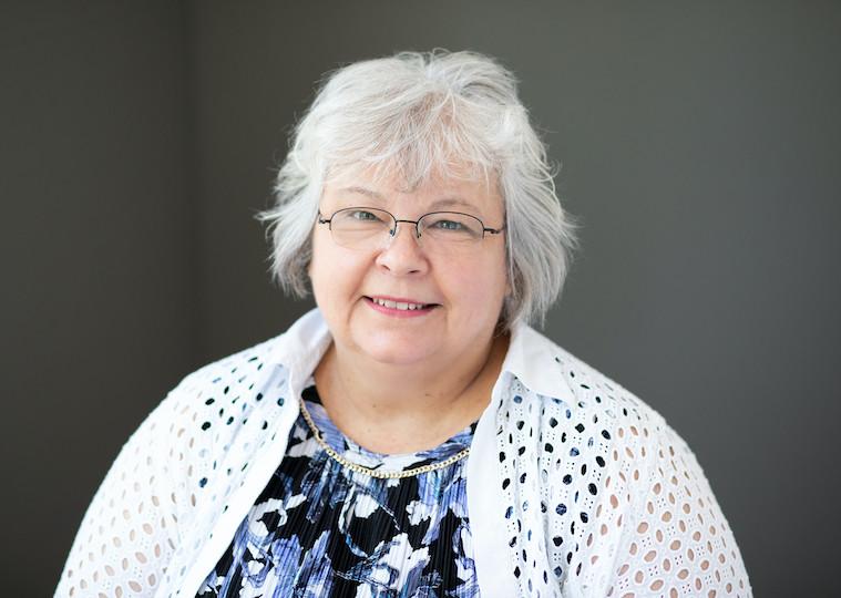 A portrait of an older woman wearing glasses.