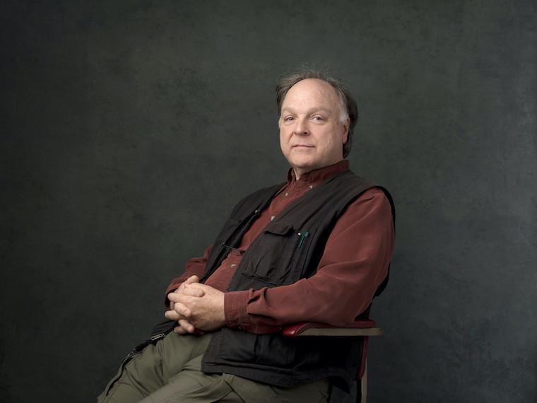 A portrait of a man reclining in an office chair.
