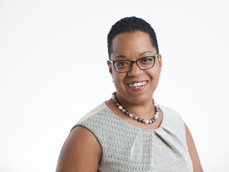 A portrait of a woman wearing a pearl necklace and glasses.