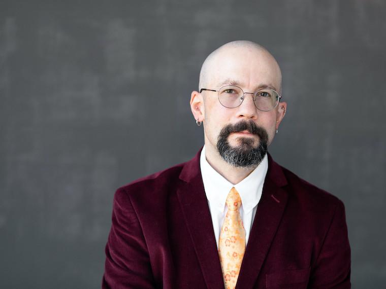 A portrait of a man wearing a velvet suit jacket.