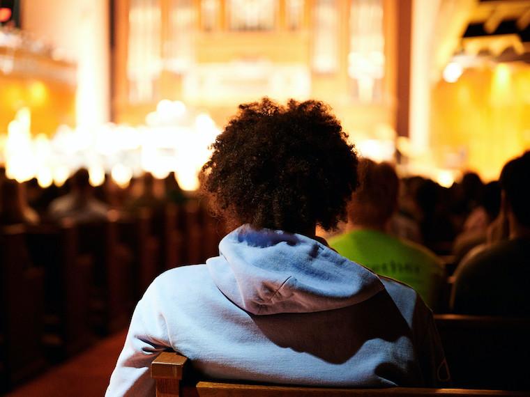 The back of a student who is facing a well lit stage,