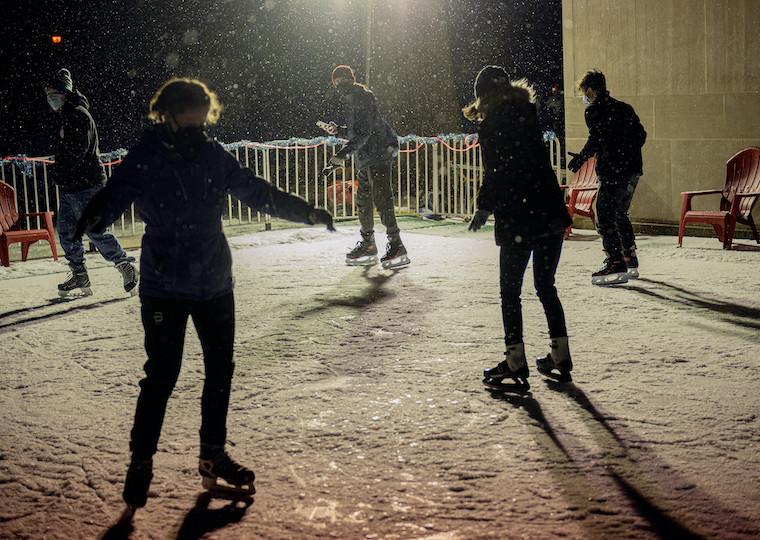 A group of people skate on an ice rink.
