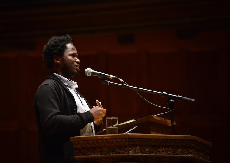A man speaks into a microphone at a podium.