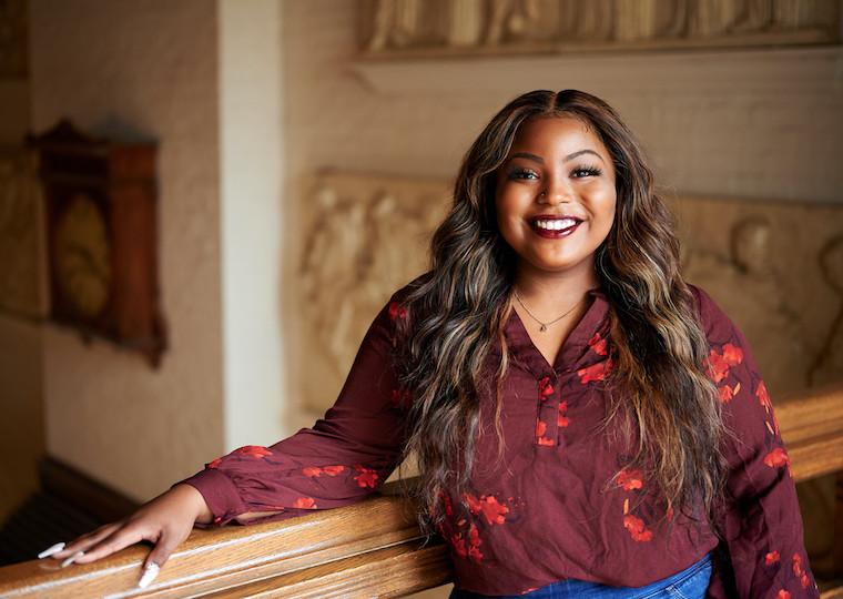 A portrait of a girl leaning on a wooden rail.